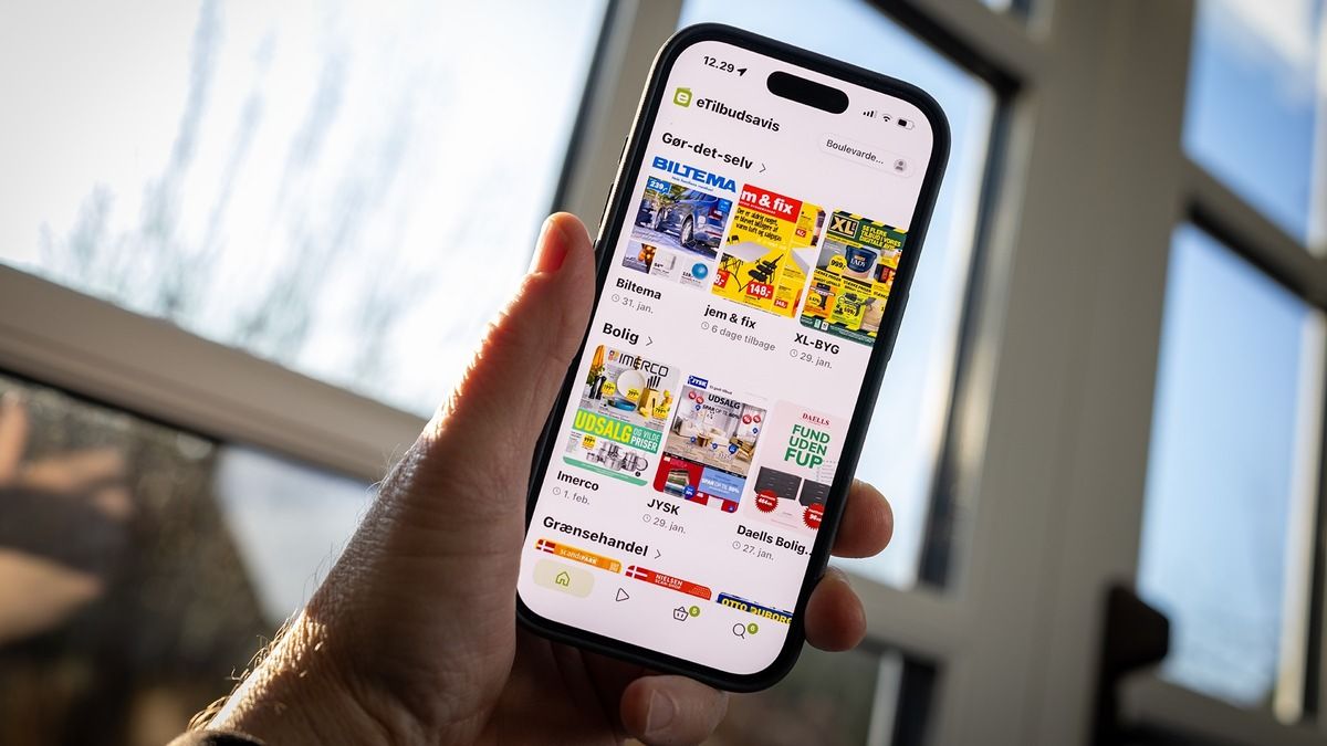Hand hält ein Smartphone mit der dänischen Prospekt-App eTilbudsavis, auf dem Bildschirm Angebotsprospekte von Baumärkten und Möbelhändlern