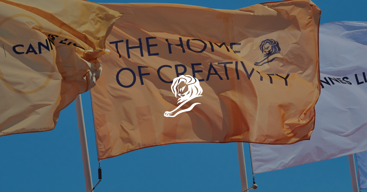Festivalflaggen von Cannes Lions vor blauem Himmel, darüber das Löwen-Logo