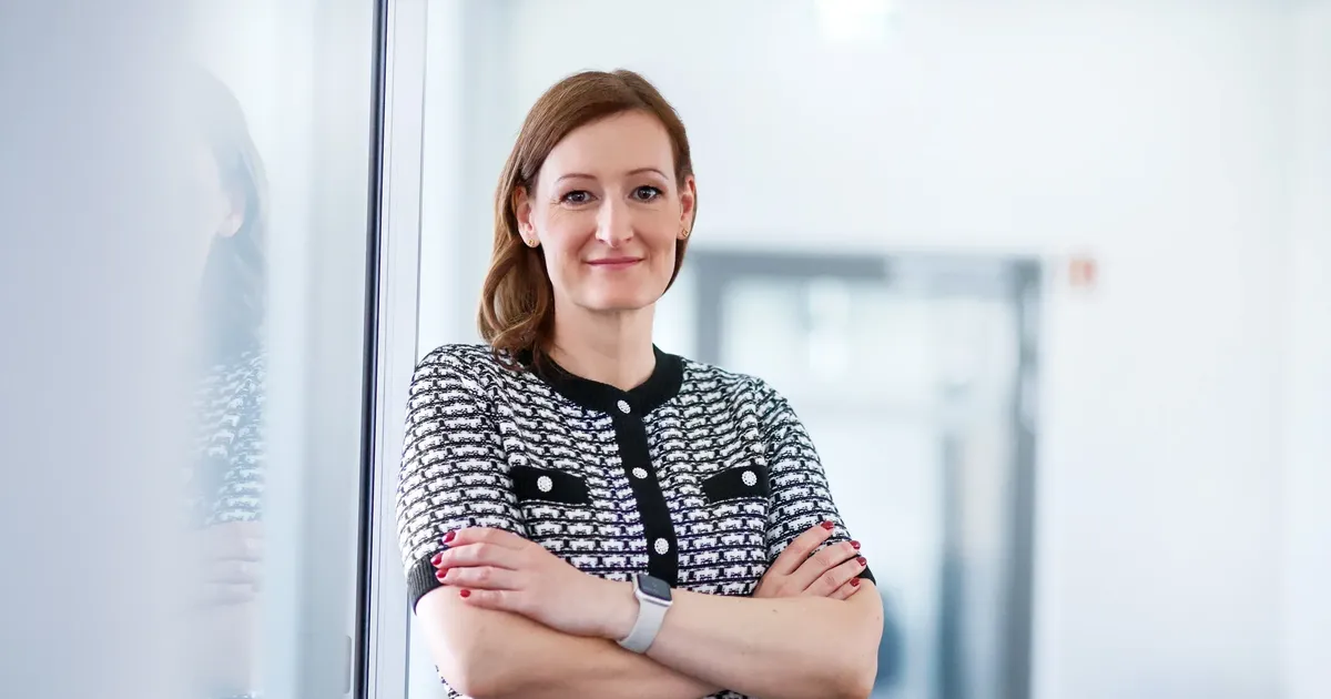 Francie Petrick mit verschränkten Armen in einem hellen Büroflur