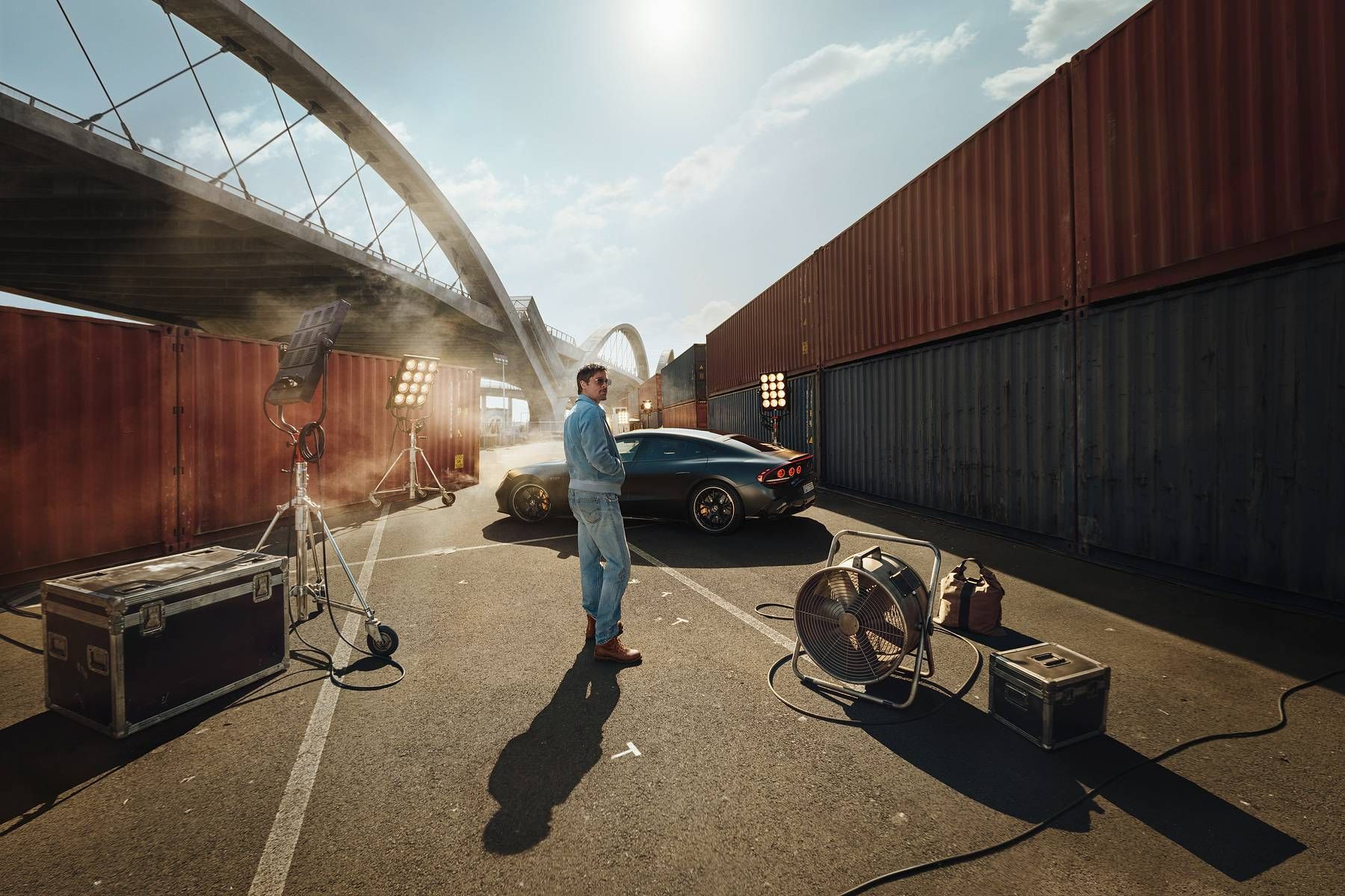 Brad Pitt steht auf einem Filmset zwischen Frachtcontainern, dahinter das Mercedes-AMG GT 4-Türer Coupé